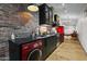 Stylish kitchen with exposed brick, black cabinets, stainless steel appliances, and red washer/dryer combo at 358 E Whitton Ave, Phoenix, AZ 85012