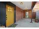 Covered porch featuring brick walls, a yellow front door, a turquoise inner door, and stylish lighting at 358 E Whitton Ave, Phoenix, AZ 85012