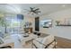Bright living room with TV, white sofa, stylish decor, modern fan, and an outdoor view at 36601 N Mule Train Rd # D1, Carefree, AZ 85377