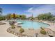 Resort-style swimming pool featuring clear blue water, rock features, lounge chairs, and vibrant desert landscaping at 36601 N Mule Train Rd # D1, Carefree, AZ 85377