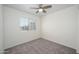 A simple, carpeted bedroom with a ceiling fan has a window with blinds and view of an adjacent home at 3755 E Broadway Rd # 21, Mesa, AZ 85206