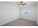 A simple, carpeted bedroom with a ceiling fan has a window with blinds and view of an adjacent home at 3755 E Broadway Rd # 21, Mesa, AZ 85206