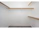A simple, walk-in closet with carpeted floors features wooden rods and shelves on a neutral-colored wall at 3755 E Broadway Rd # 21, Mesa, AZ 85206