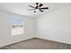 Neutral bedroom boasts a ceiling fan, a large window, and neutral carpeting at 51210 W Bluejay St, Maricopa, AZ 85139