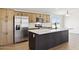 Modern kitchen with wood cabinets, stainless steel appliances, and a dark center island with stone countertops at 51210 W Bluejay St, Maricopa, AZ 85139