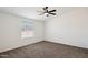 A bright bedroom with a ceiling fan, carpet and view from a window at 51288 W Bluejay St, Maricopa, AZ 85139