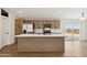 Modern kitchen featuring an island, stainless steel appliances, and wood-grain cabinetry at 51288 W Bluejay St, Maricopa, AZ 85139