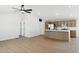 Open-concept space with wood-look floors, ceiling fan, and modern kitchen island at 51288 W Bluejay St, Maricopa, AZ 85139