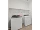 Modern laundry room with front loading washer and dryer and overhead shelf at 5537 S 246Th Ave, Buckeye, AZ 85326