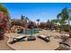 Resort-style pool featuring a rock waterfall, blooming bushes, an umbrella stand and two lounge chairs at 5755 S Pearl Dr, Chandler, AZ 85249