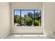 A sunlit room with a large window showcasing a backyard with pool, lush trees and waterfall feature at 6467 E Sierra Vista Dr, Paradise Valley, AZ 85253