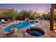 Backyard pool and spa area surrounded by stone landscaping with an outdoor fireplace and relaxing lounge seating at 7547 E Mary Sharon Dr, Scottsdale, AZ 85266
