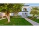 Charming white two-story home with lush green lawn, mature landscaping, and a gated entry at 7684 E Minnezona Ave, Scottsdale, AZ 85251