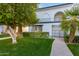 Charming white two-story home with lush green lawn, mature landscaping, and a gated entry at 7684 E Minnezona Ave, Scottsdale, AZ 85251
