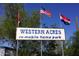 Sign at Western Acres RV-Mobile Home Park with welcoming flags in the background at 9913 E Main St # 40, Mesa, AZ 85207