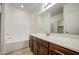 Bright bathroom with a tub, a brown vanity with solid surface countertops, and a large mirror at 10430 E Sunflower Ln, Florence, AZ 85132