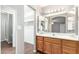 Bright bathroom with wooden vanity, large mirror, and open view to the main bedroom and walk-in closet at 11510 E Lomita Ave, Mesa, AZ 85209