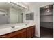 Dual sinks and a large mirror highlight this bathroom with a walk-in closet at 17878 N 114Th Ln, Surprise, AZ 85378