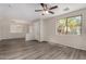 Bright living room features gray wood floors, a ceiling fan, and natural light at 17878 N 114Th Ln, Surprise, AZ 85378