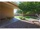 Relaxing backyard patio with desert landscaping, a large shade tree, and ample open space at 18116 N Catherine Dr, Surprise, AZ 85374