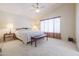 Spacious main bedroom features a ceiling fan, large window, neutral carpeting, and a comfy bed with bench at 18116 N Catherine Dr, Surprise, AZ 85374