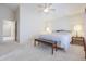 Bright main bedroom boasts neutral carpet, a ceiling fan, and a comfortable bed with bench seating at 18116 N Catherine Dr, Surprise, AZ 85374