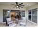 Covered back patio with ceiling fan, stone floors, and comfortable seating, leading to outdoor living spaces at 18175 W Highland Ave, Goodyear, AZ 85395
