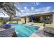 Inviting backyard with a sparkling pool, manicured lawn, shaded patio, and lush landscaping ideal for relaxation at 18175 W Highland Ave, Goodyear, AZ 85395