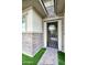 Covered porch with a brick floor, a secure metal screen door, and manicured artificial turf at 18175 W Highland Ave, Goodyear, AZ 85395
