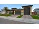 Modern home with a three-car garage, manicured artificial lawn, and a brick driveway at 18175 W Highland Ave, Goodyear, AZ 85395