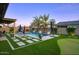 Backyard oasis featuring a pristine pool, lush landscaping, and fire features under a beautiful dusk sky at 18175 W Highland Ave, Goodyear, AZ 85395