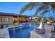 Relaxing pool with integrated fire bowls, an outdoor kitchen, and covered dining space at 18175 W Highland Ave, Goodyear, AZ 85395
