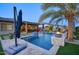 Beautiful pool with travertine tile, an umbrella, integrated fire bowls, and outdoor entertaining area at 18175 W Highland Ave, Goodyear, AZ 85395