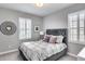 Neutral bedroom showcasing a gray upholstered bed frame, white shutters and ample natural light at 214 W Beverly Ln, Phoenix, AZ 85023
