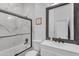 Modern bathroom featuring marble tile, a glass shower door, and a dark framed mirror at 22346 N 104Th Ln, Peoria, AZ 85383