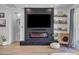 Bright living room with a modern fireplace, TV, comfortable chair, and shelves with decorative items and plants at 22346 N 104Th Ln, Peoria, AZ 85383