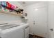 Bright laundry room with storage shelves above the modern, front-loading washer and dryer, and convenient exterior access door at 3418 W Maldonado Rd, Phoenix, AZ 85041