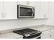 Close-up of a kitchen with white cabinets, granite countertops, and stainless steel appliances at 37069 W Prado St, Maricopa, AZ 85138