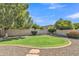 Landscaped backyard featuring lush lawn, brick-lined border, mature trees, and gravel ground cover at 4061 E Hope St, Mesa, AZ 85205