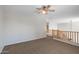 Open loft area with neutral paint, ceiling fan, and wooden railing at 43507 W Cydnee Dr, Maricopa, AZ 85138
