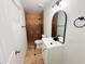 Bathroom with a tiled shower, vanity sink, and a modern, arched mirror with black hardware at 5338 W Wolf St, Phoenix, AZ 85031