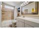 Clean bathroom with a shower-tub, vanity, a mirror and a glass block window for privacy at 7736 E Hazelwood St, Scottsdale, AZ 85251