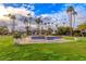 Serene community park featuring a beautiful fountain, surrounded by lush green lawns and towering palm trees at 7736 E Hazelwood St, Scottsdale, AZ 85251