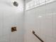 Modern bathroom shower with white tile and bronze fixtures, including shower head and grab bar at 7736 E Hazelwood St, Scottsdale, AZ 85251
