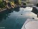 Backyard pool enclosed with a safety net over dark water, rock waterfall, and light stone coping at 8441 W Foothill Dr, Peoria, AZ 85383