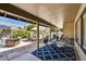 Covered patio with stone flooring, outdoor seating, grill, and lush landscaping at 9226 W Topeka Dr, Peoria, AZ 85382