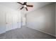 A carpeted bedroom with gray walls, closet, access to an adjacent bathroom, and a ceiling fan at 14262 N 142Nd Ln, Surprise, AZ 85379