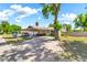 Long driveway leads to a home with a covered carport, turquoise doors, and a mature shade tree at 1451 E Brown Rd, Mesa, AZ 85203