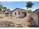 A backyard featuring a patio and drought-tolerant landscaping, including palm trees and gravel at 14793 W Surrey Dr, Surprise, AZ 85379