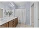 Bright bathroom featuring double sinks with wood cabinets and a shower with a white curtain at 14793 W Surrey Dr, Surprise, AZ 85379